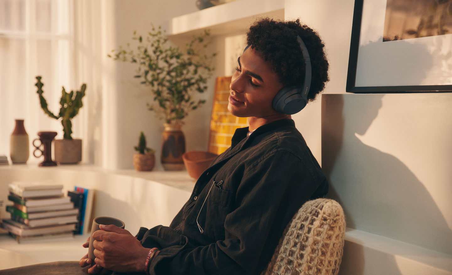 Image of a man at home enjoying listening to music with a black pair of Sony WH-CH720 headphones